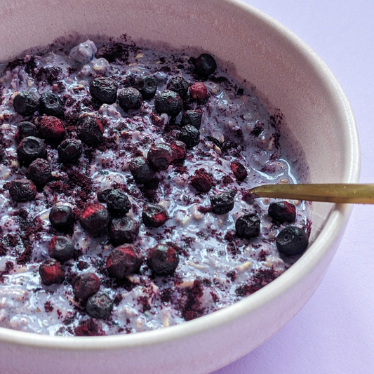 Bowl of blueberry & black currant overnight oats topped with blueberries