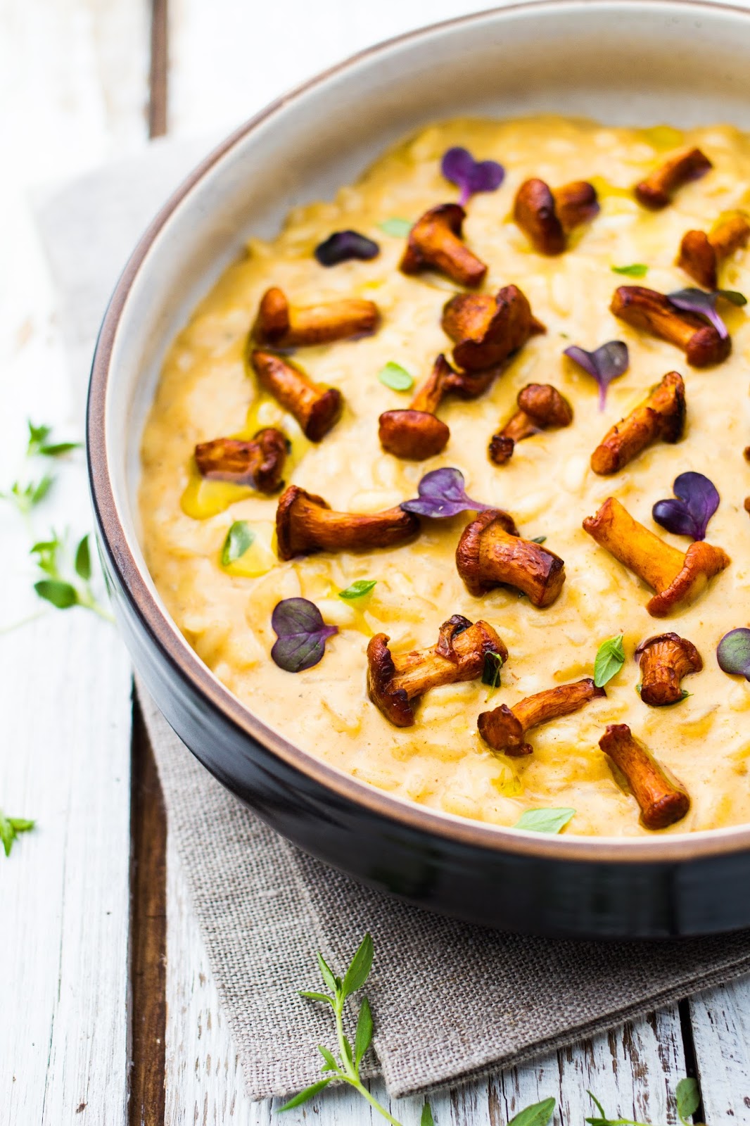 A bowl of chanterelle risotto on top of a white wooden table